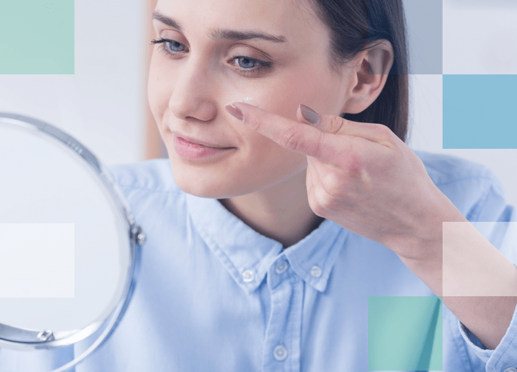 Blue eyed woman putting contact lens in left eye