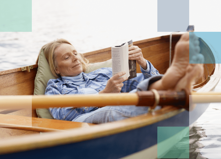 Older woman reading a book on a row boat with her feet up