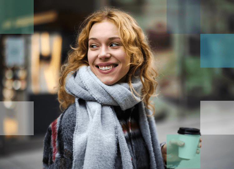 Light color haired woman with a scarf and a cup of coffee smiling wearing daily contact lenses