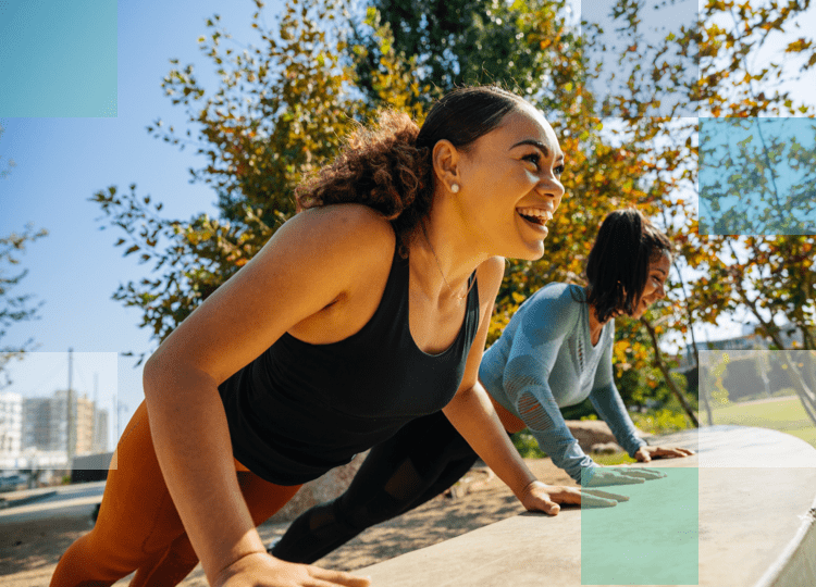 Two women doing exercise in a park smiling