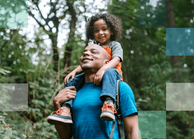 Parent and child walking through lush green forest on a hike