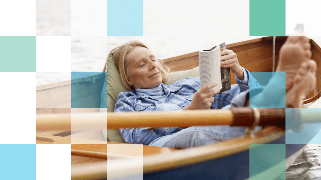 Older woman reading a book on a row boat with her feet up