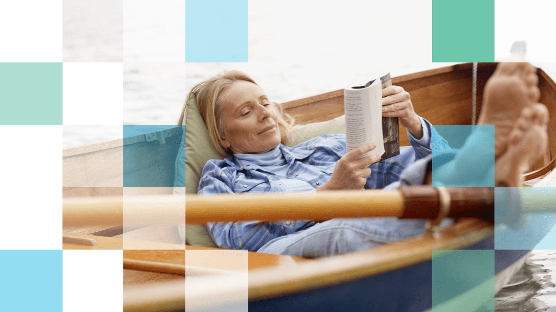 Older woman reading a book on a row boat with her feet up