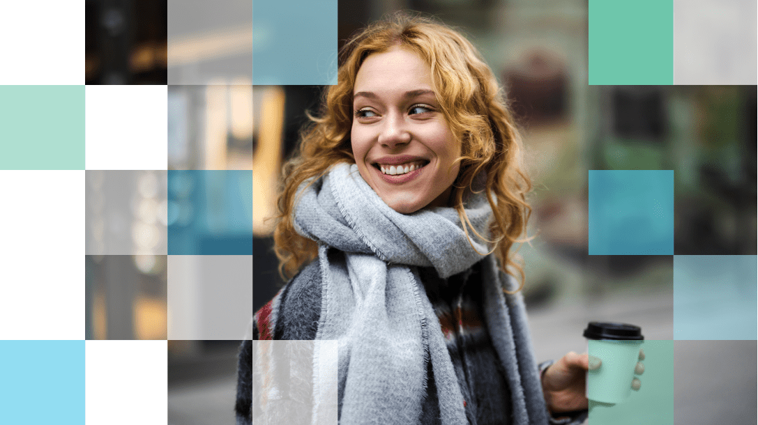 Light color haired woman with a scarf and a cup of coffee smiling wearing daily contact lenses