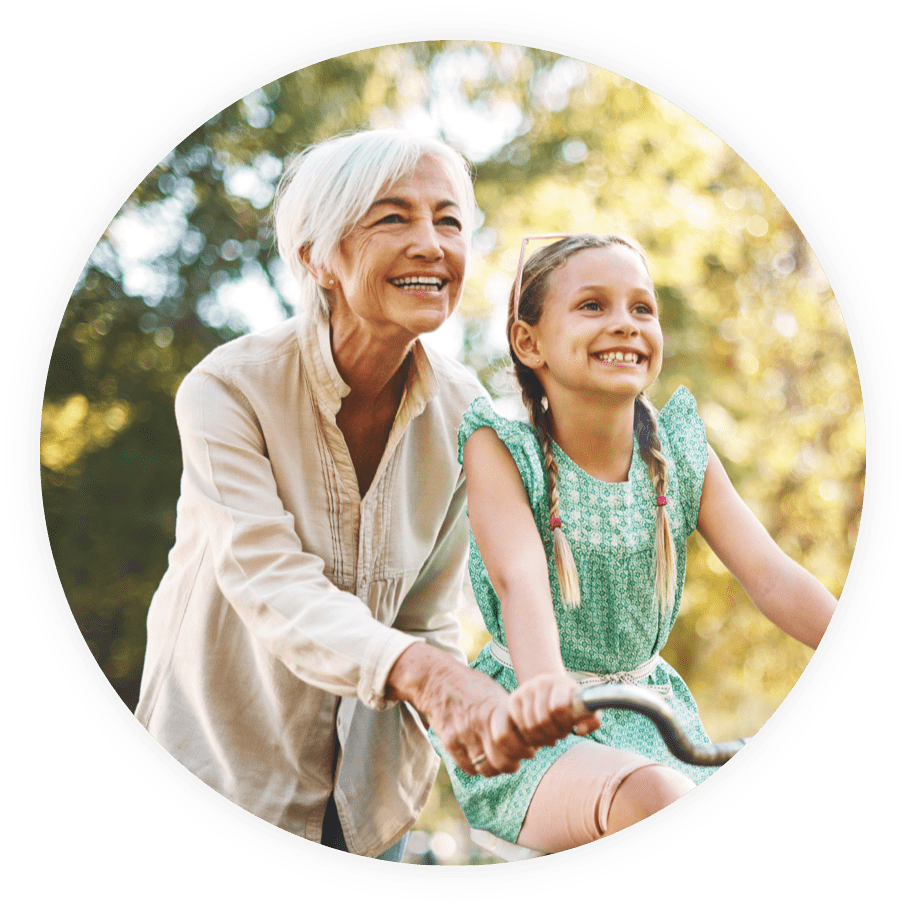 Grandparent and grandchild outside riding a bike together and smiling